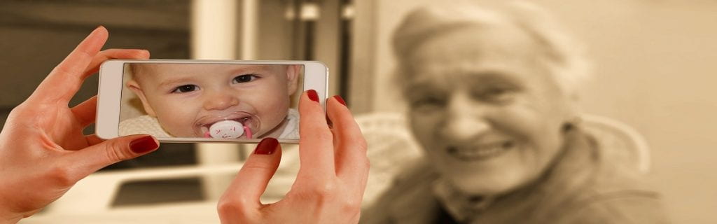 a smartphone with a baby's image facing an elderly woman